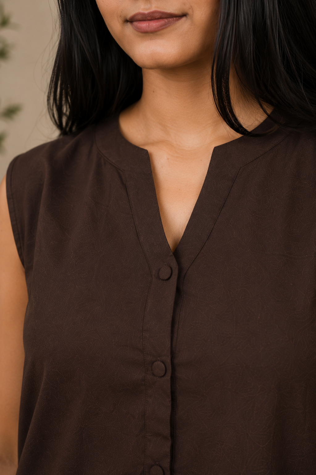 Brown sleeveless top worn by a person with a neutral background